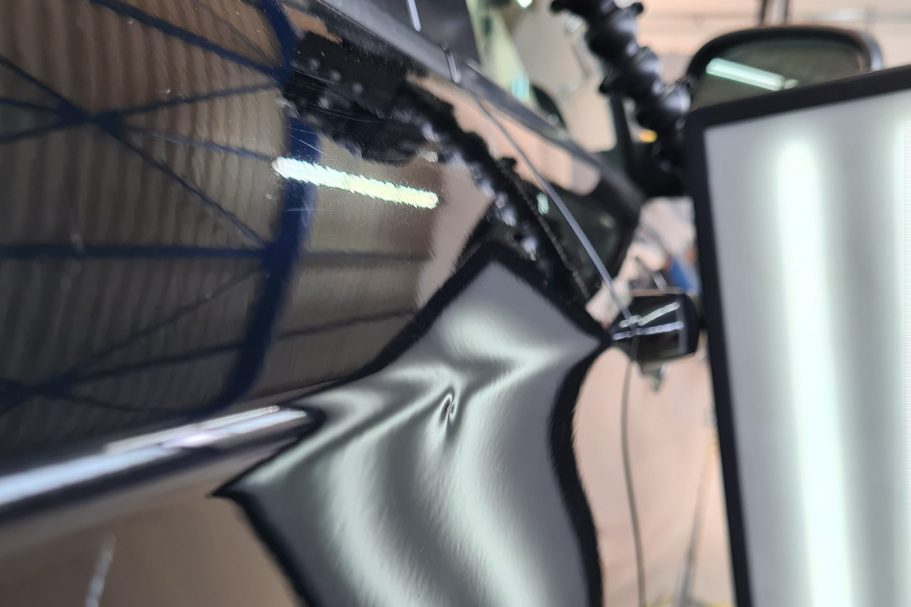 Delle in der Autotür Eine Delle an einer schwarzen Autotür, direkt auf der Designkante, sichtbare Delle mittels einer Reflektion LED-Streifenlampe.
